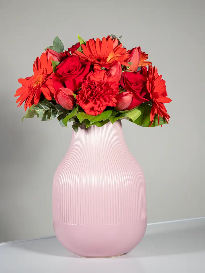 Bouquet rosso di gerbere rose tulipani in vaso rosa